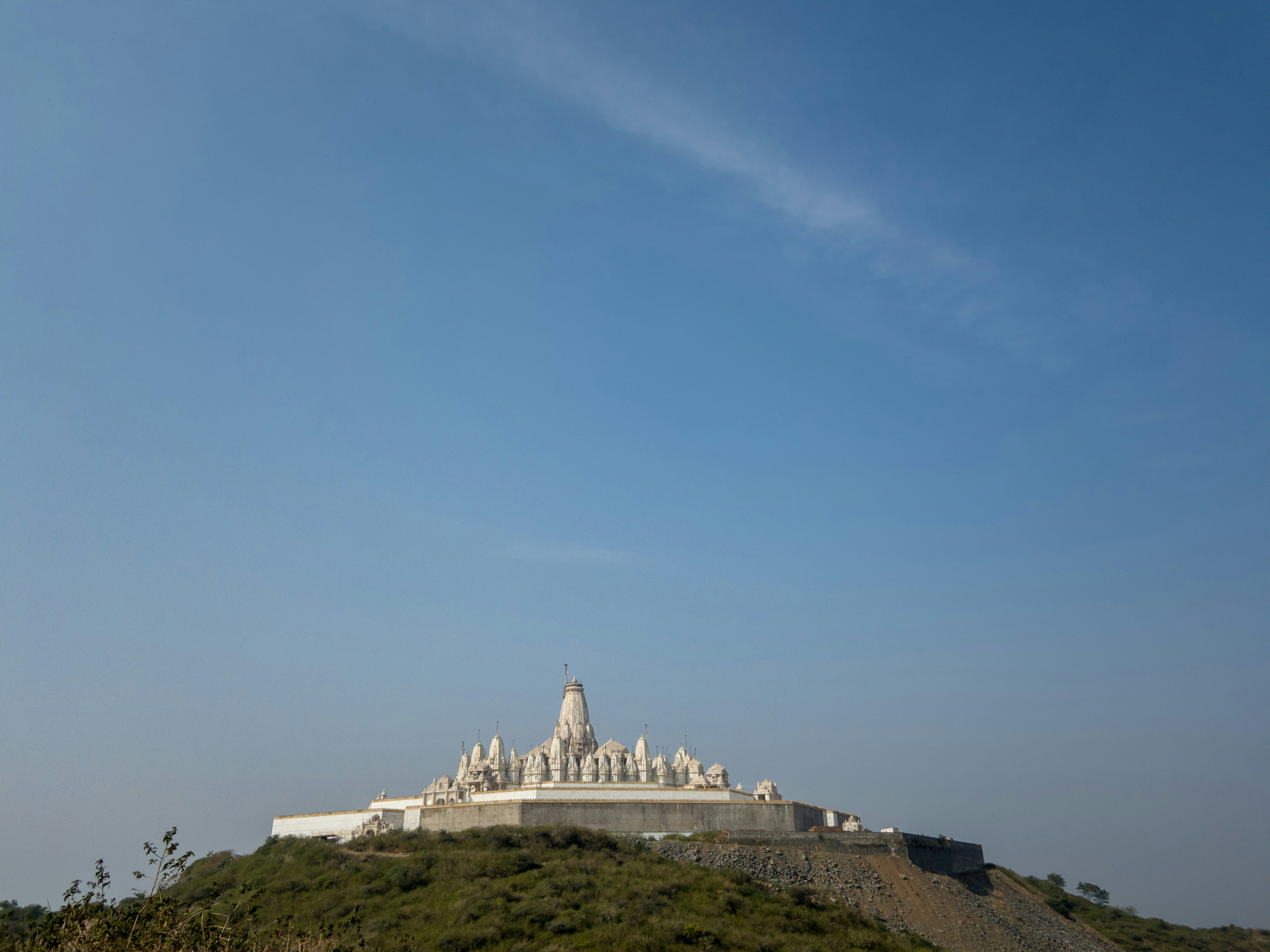 white concrete building on top of hill under blue sky during daytime